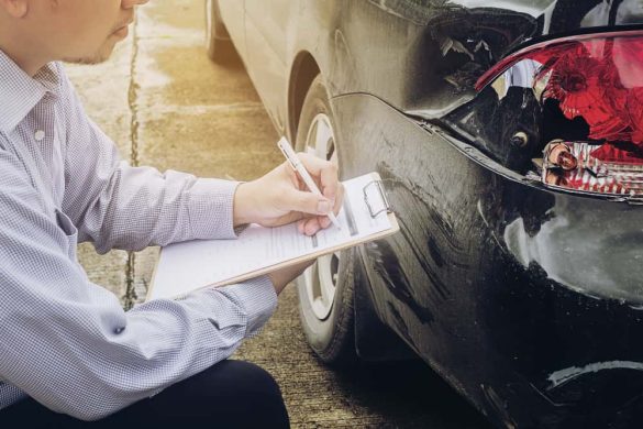Un expert en assurance voiture au Maroc remplit un constat amiable à côté d'un véhicule noir endommagé à l'arrière.