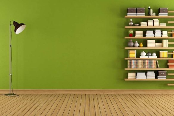 Une bibliothèque murale constituée d'étagères en bois fixées sur un mur vert clair dans un intérieur épuré.