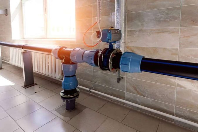 Installation de tuyauterie industrielle intérieure avec des vannes et un clapet anti-retour intégré sur des conduits en PVC bleu.